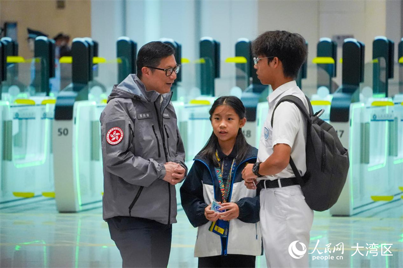 圖6:香港特區政府保安局局長鄧炳強向旅客詢問過關情況。人民網 吳宇颺颺攝