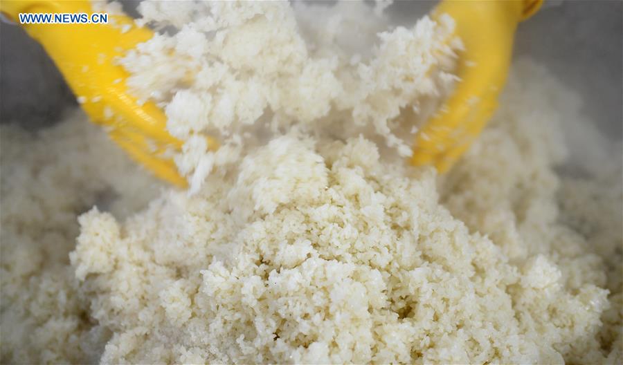A worker mixes glutinous rice with lard oil and sugar to make eight-treasure rice pudding at a workshop in Zunyi, southwest China