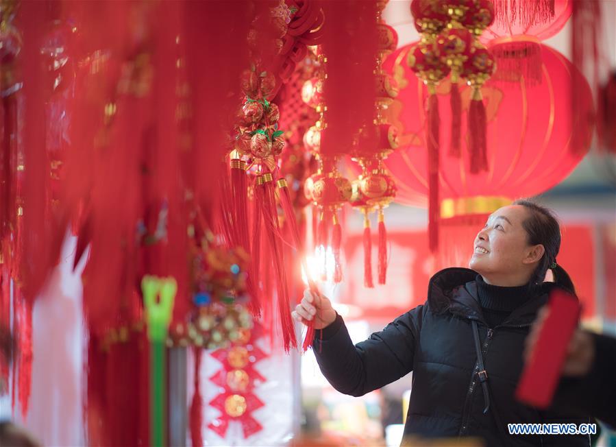 A resident selects goods at a shopping fair held to greet the upcoming Spring Festival at Wuhan International Conference & Exhibition Center in Wuhan, capital of central China