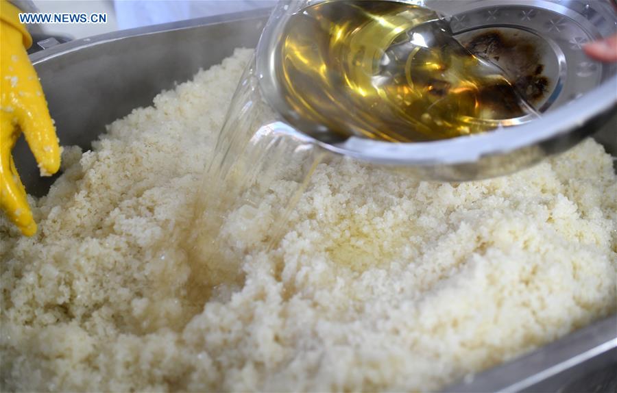 A worker pours lard oil into glutinous rice to make eight-treasure rice pudding at a workshop in Zunyi, southwest China